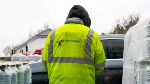 A person in a yellow high-vis coat on. It says South East Water on the back.