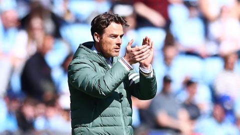 Burnley manager Scott Parker,  wearing a padded coat, standing pitch side encouraging his players