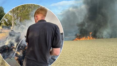 Farmers battle blaze on farmland. A ginger man holds equipment, firing water at a fire with thick black smoke.