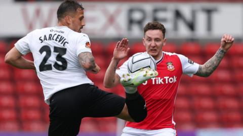 Antoni Sarcevic of Stockport County and Wrexham's Callum McFadzean compete for the ball