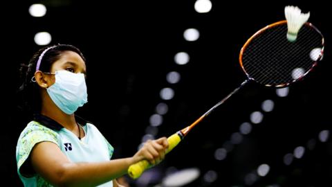 A badminton player plays in a mask