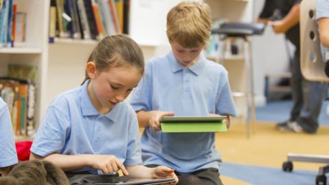 school children in library using tablets