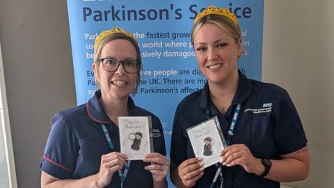 Amy Cheevers and Holly Musgrave wearing their blue nurses uniforms and gold tiaras holding the nursing awards 