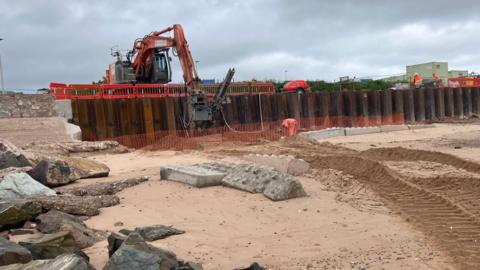 Plant machinery putting a steel sea wall in place in Exmouth