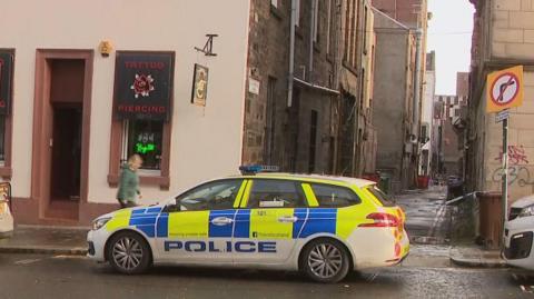 A police car parked in front of an alleyway