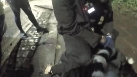 A police officer sat on top on a woman on the ground