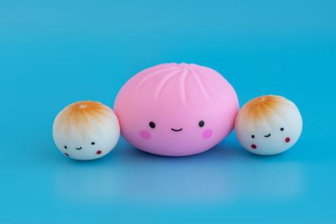 3 squishy fidget toys that look like dumplings with smiley faces appear on a blue background