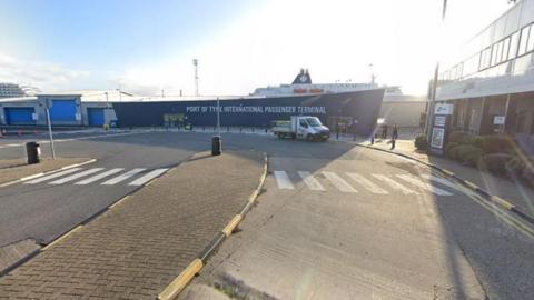 A general view of the outside of the Port of Tyne International Passenger Terminal with a ferry in the background and a flat-bed truck parked outside