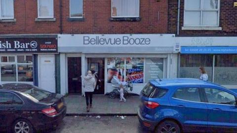 A Google Street View screenshot of Bellevue Booze pictured from the street. The shop has its name in grey lettering against a white background.