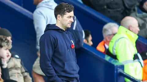A photo of West Bromwich Albion boss Ryan Mason wearing a blue hoodie and a poppy