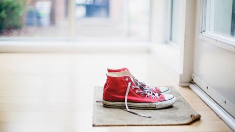 A pair of red shoes sitting on a door matt inside a house. stock image