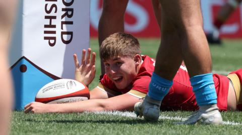 Steffan Emanuel lies on the line with the ball and celebrates scoring his second try for Wales Under-20s against Uruguay