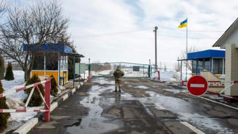 A Ukrainian soldier stands guard at the check point on the border with Russia