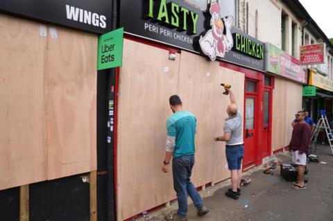 Two people boarding up a fast food shop