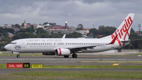 A Virgin Australia Boeing 737-800 series aircraft on the runway at Sydney's main international airport.