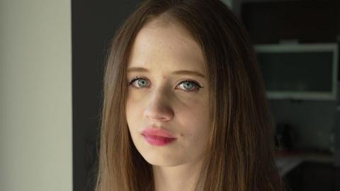A portrait of Viktoria, a young woman with long, brown hair and blue eyes, pictured close-up and facing the camera
