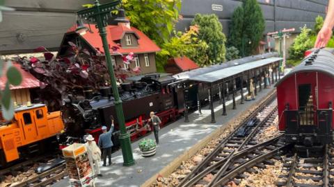 Model trains in the garden display - there's a platform in the centre of the rails with some model figures standing on it