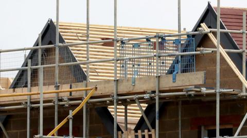 Scaffolding surrounding the roofs of new houses being constructed.