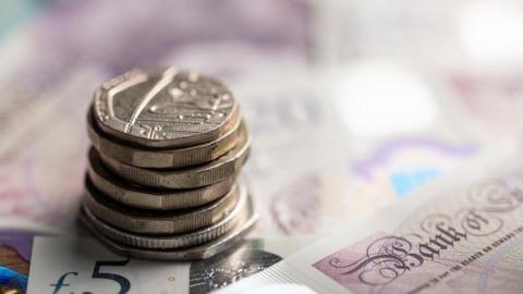 A pile of coins on top of Bank of England notes