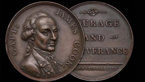 A bronze-toned commemorative medal is shown with both sides visible against a dark background
