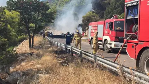 Firefighters at the scene where to helicopters collided. Three men stand next to two fire engines