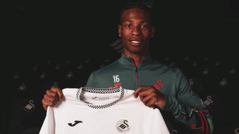 Ishe Samuels-Smith holds a Swansea City shirt