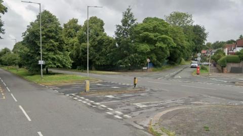 A treelined dual carriageway junction with two side roads.