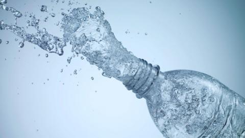 An open bottle of water with water coming out of the top