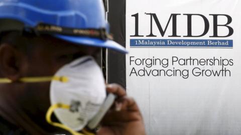 A construction worker talks on the phone in front of a 1Malaysia Development Berhad (1MDB) billboard at the Tun Razak Exchange development in Kuala Lumpur, Malaysia, in this 3 February 2016 file photo