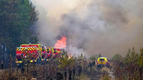 Fire engines battling a wildfire with thick smoke in the area, in France.