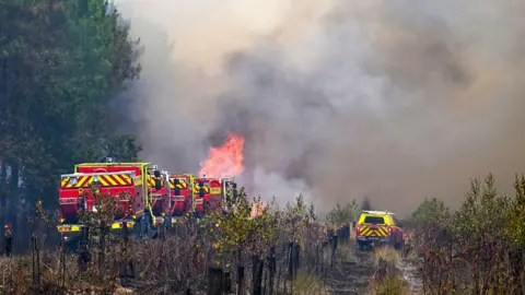 Fire engines battling a wildfire with thick smoke in the area, in France.