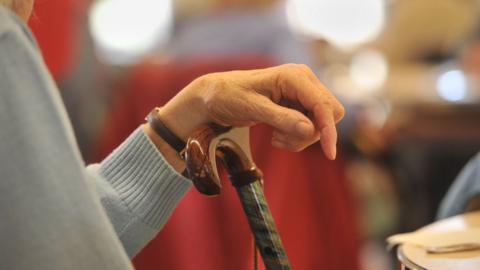 Elderly lady's hand on walking stick