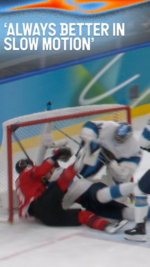 Canadian and Finnish Ice hockey players falling over each other, into the net