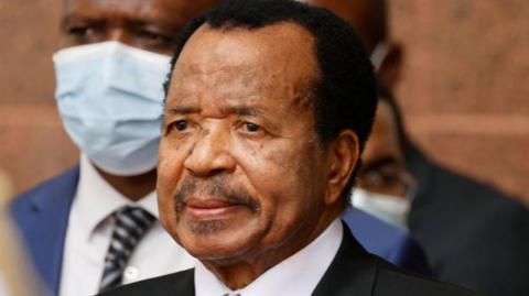 A headshot of Paul Biya wearing a dark suit and white shirt.