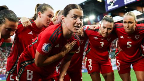 Wales captain Angharad James talks to the team in a huddle on the pitch at Euro 2025