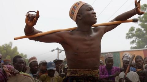 Fulani man with a stick across his shoulder