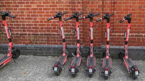 Red electric scooters parked in a line on the pavement in Bristol, England