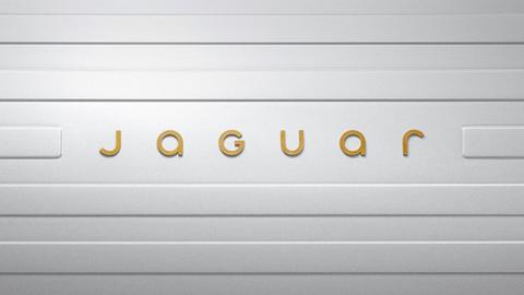 The word Jaguar in gold letters spaced out on a grey striped background.