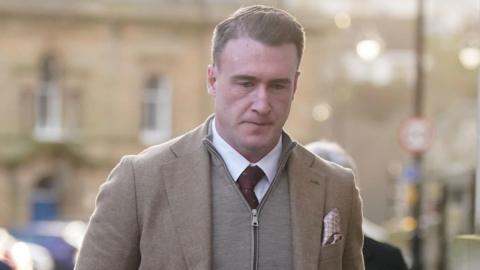 Former Scotland rugby captain Stuart Hogg in a grey zip-up top with a jacket over the top and a purple tie on a white shirt
