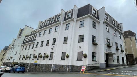 A corner view of a four story white building. 