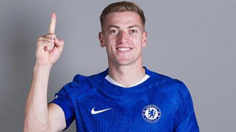 Liam Delap puts his finger up while wearing a Chelsea shirt
