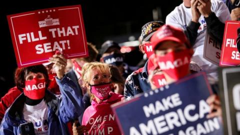 Trump supporters hold a sign telling Trump to fill the seat