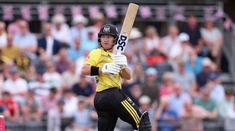 D'Arcy Short looks over his shoulder while holding the bat in the air during a match for Gloucestershire