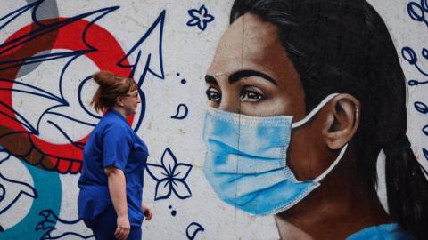 A nurse walking past a Covid mural