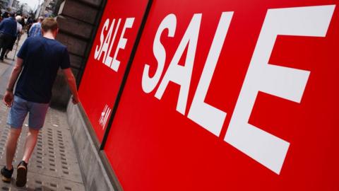 Man walks past sale sign