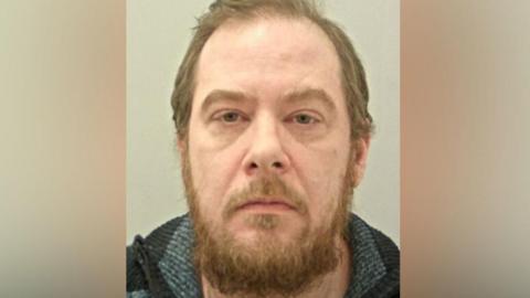 Police custody image Chris Wearing with brown hair beard wearing a grey and black knitted jumper