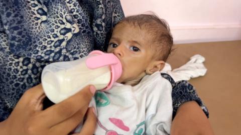 Yasmeen Abu Sultan feeds her two-year-old daughter a bottle