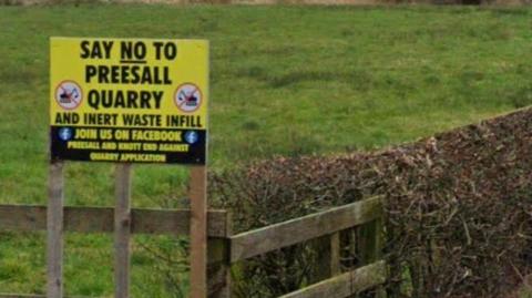 Black on yellow sign at the side of a hedge and field off a country lane that says 'say no to Preesall quarry'