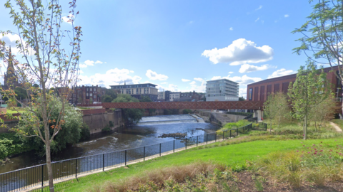 The Forge Island Canal area with a red bridge and greenery.