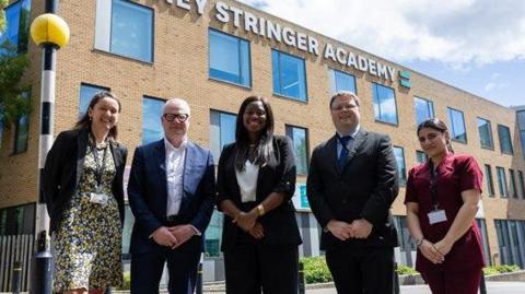 The Mayor of the West Midlands Richard Parker stands in front of the Sidney Stinger Academy with members of staff from both the school and Coventry College, as well as Government Minister Miatta Fahnbulleh.